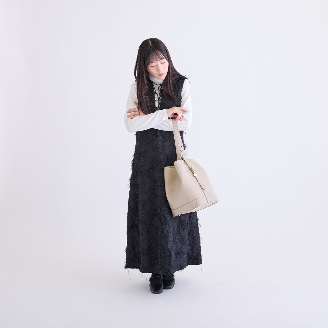 アイボリーのLサイズ巾着ボストンバッグを腕に掛けた女性