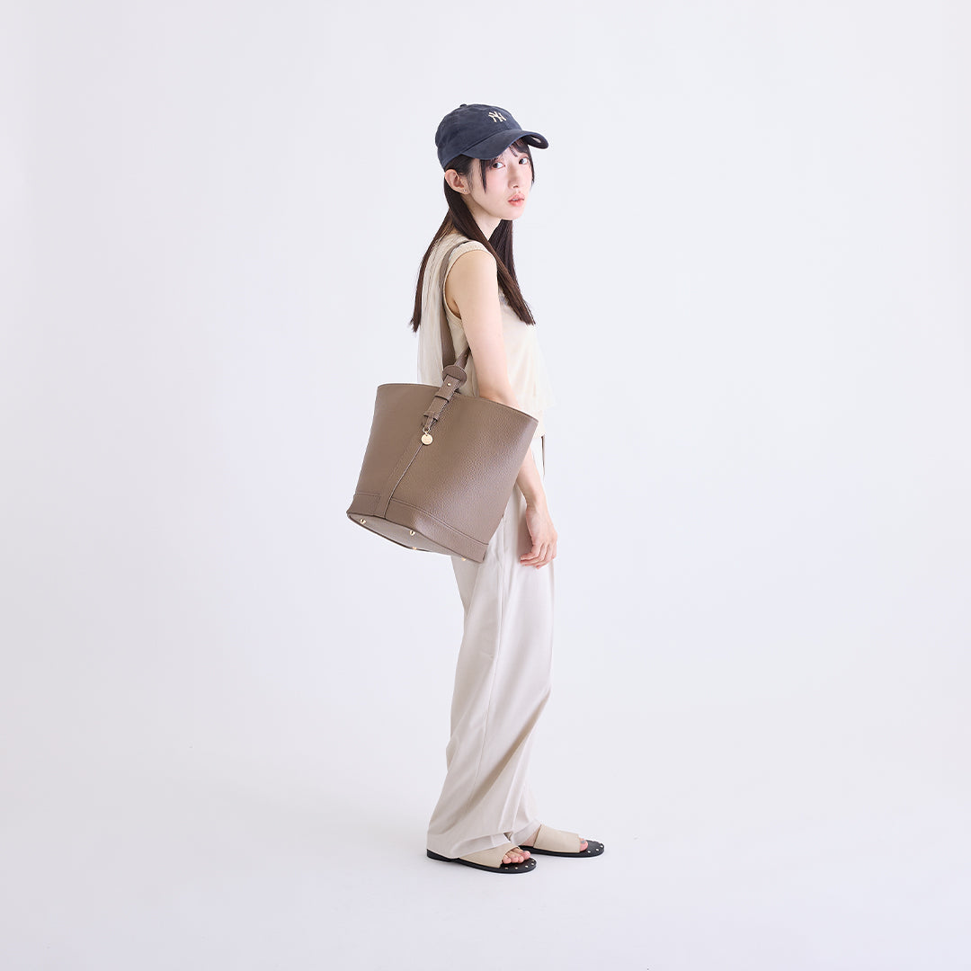 トープのLサイズ巾着ボストンバッグを肩掛けした女性