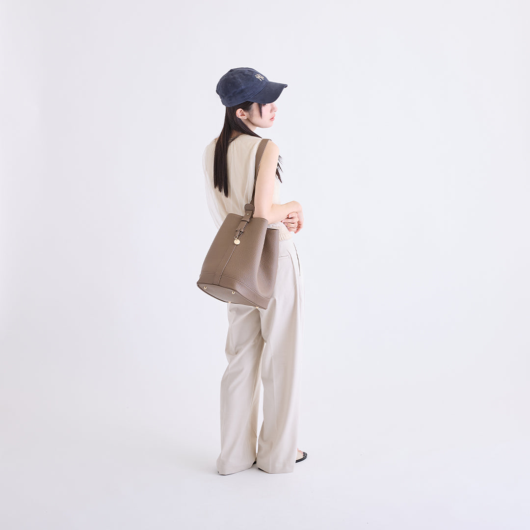 トープのLサイズ巾着ボストンバッグを肩に掛けた女性