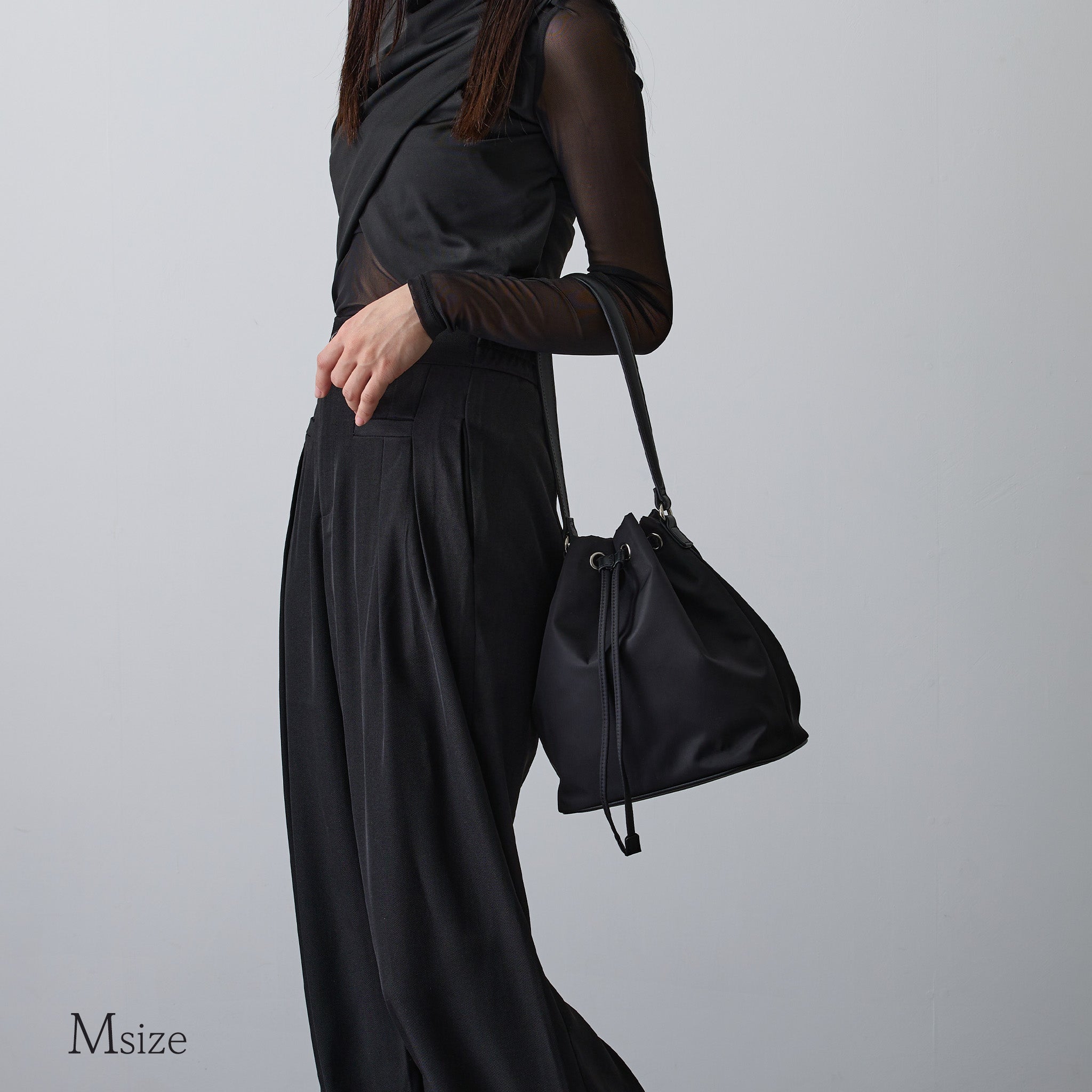 黒ナイロン巾着バッグMサイズを肩掛けする女性