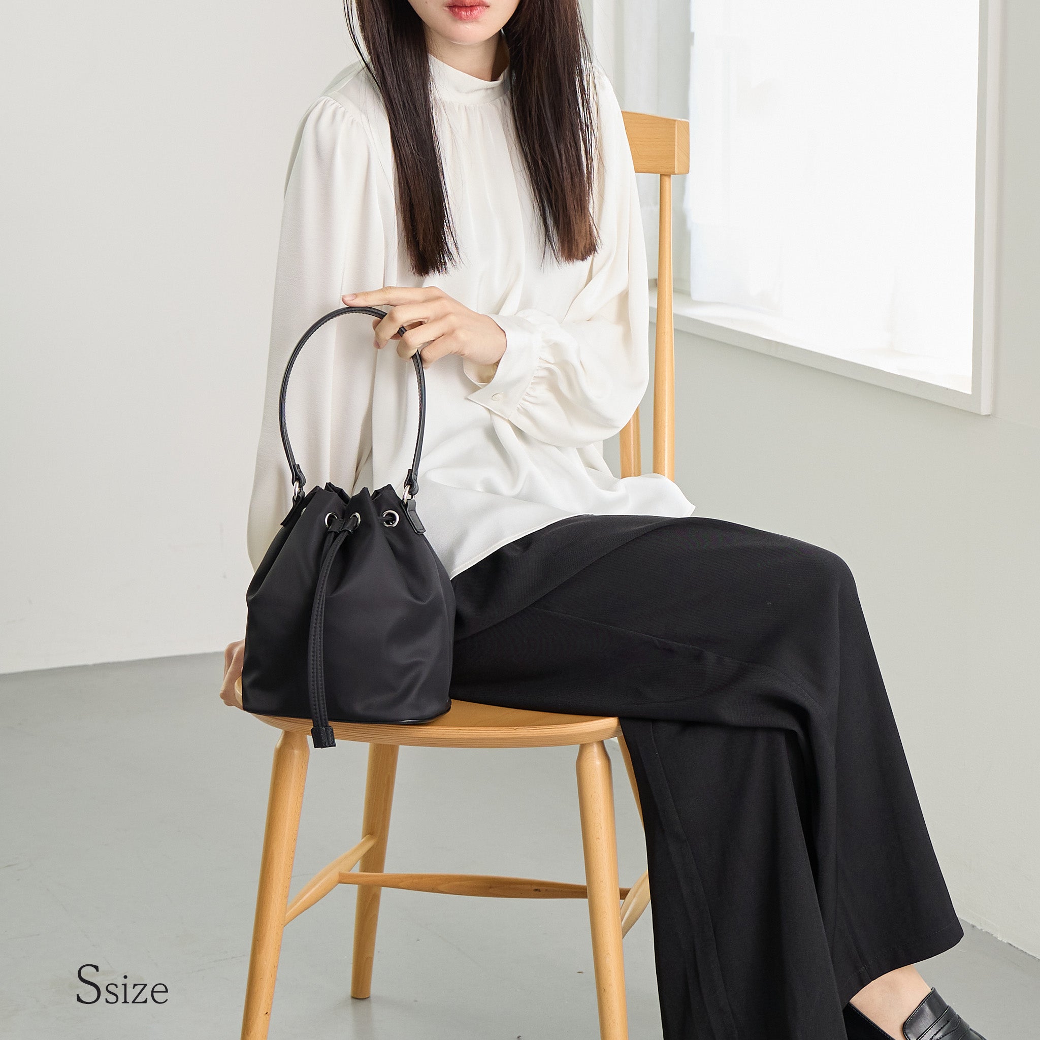 黒ナイロン巾着バッグSサイズを手に持つ女性 ナチュラルコーデ