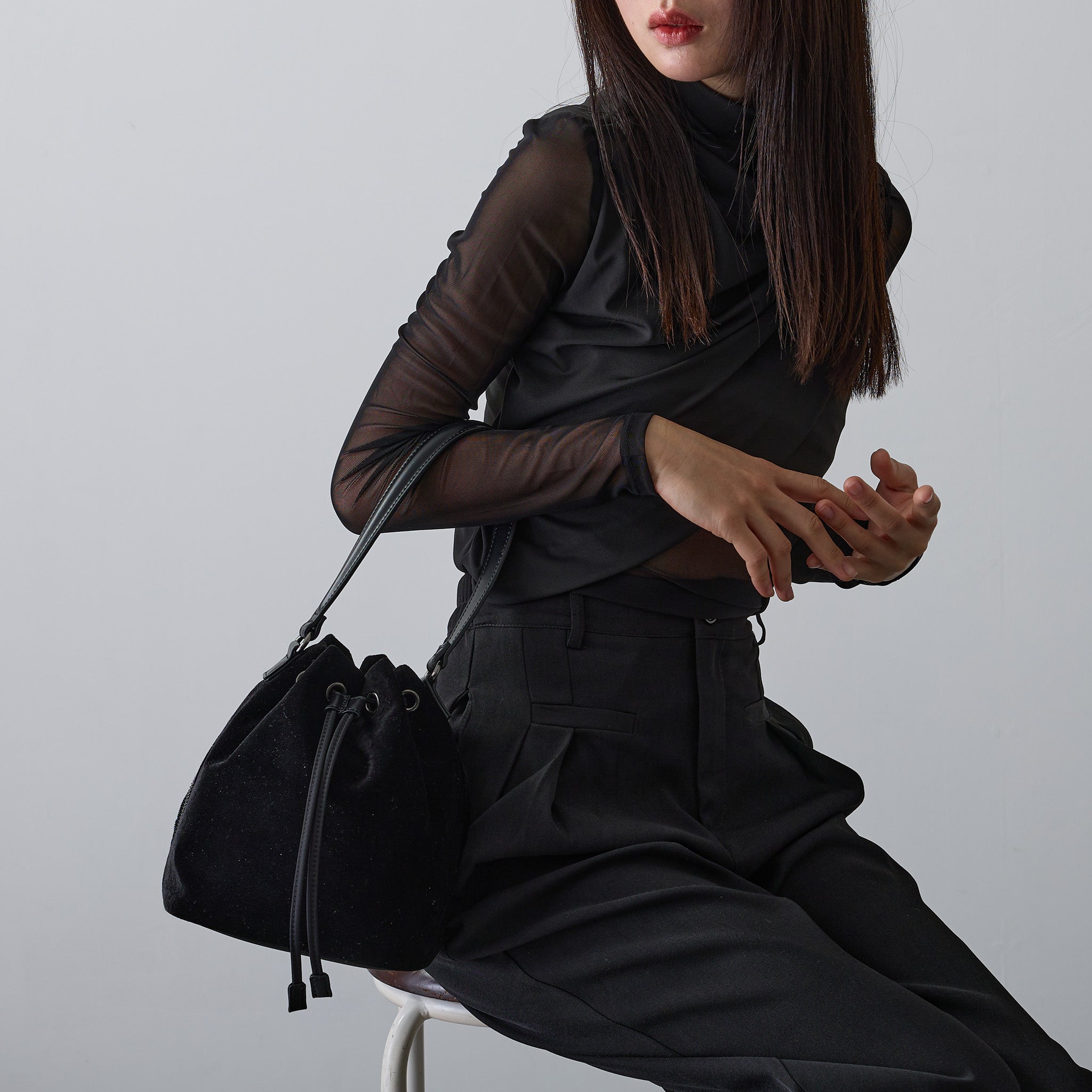 黒ベロア巾着バッグを肩掛けする女性 モード系コーデ