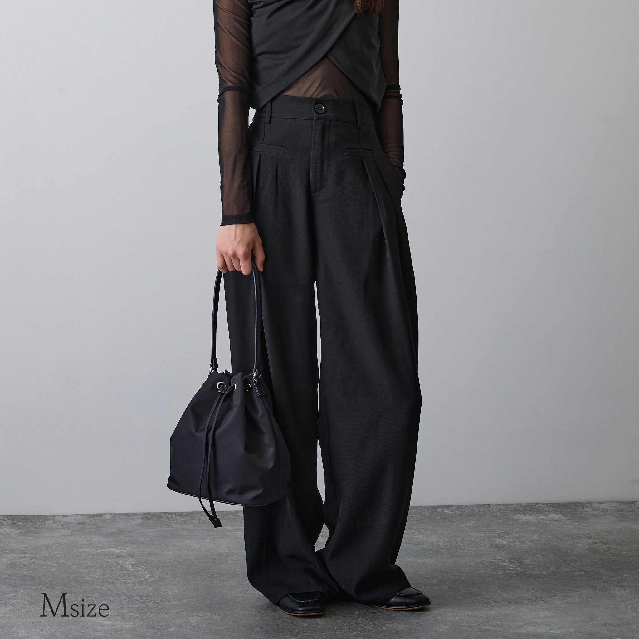 黒ナイロン巾着バッグMサイズを手に持つ女性の全身コーデ