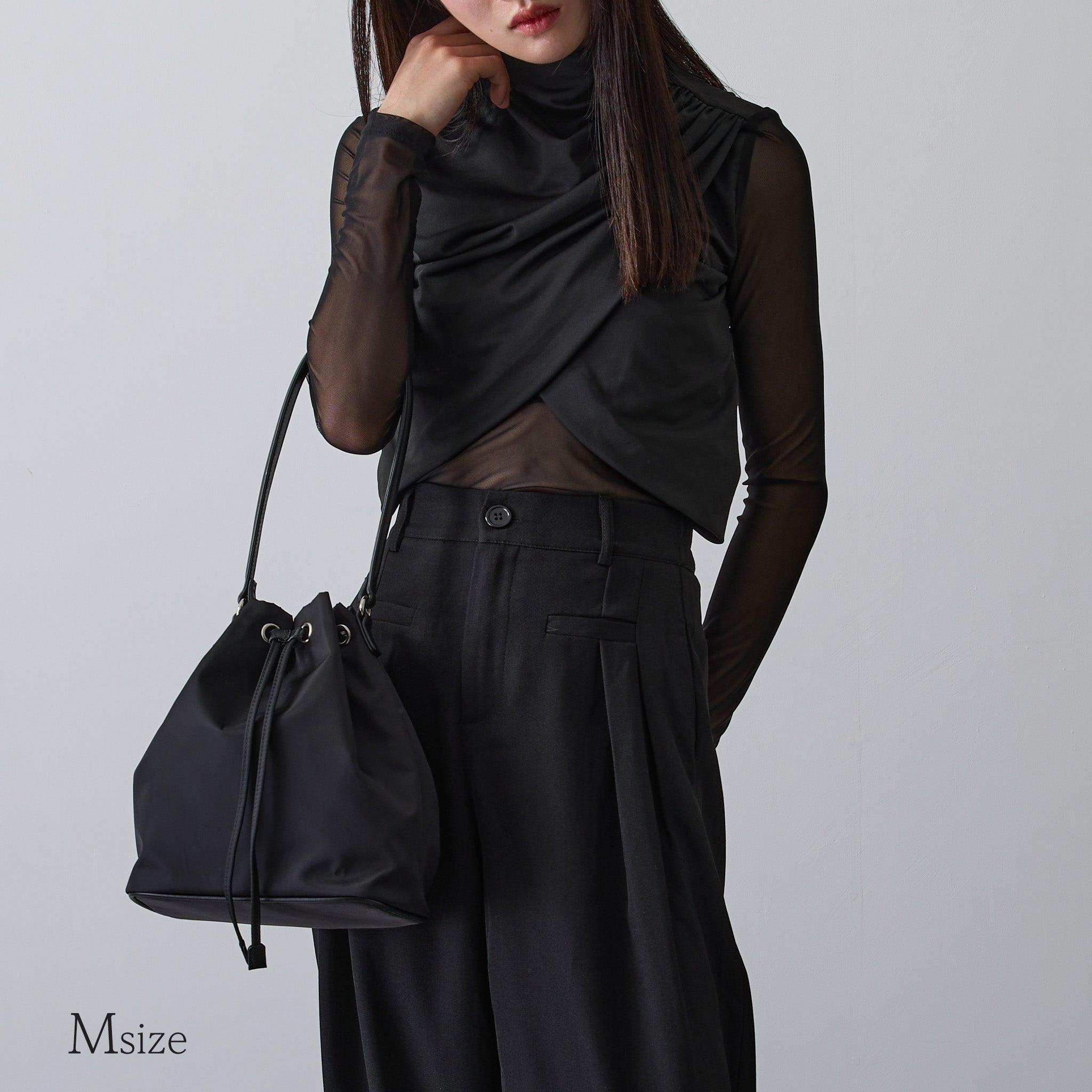 黒ナイロン巾着バッグMサイズを肩掛けする女性 モード系コーデ