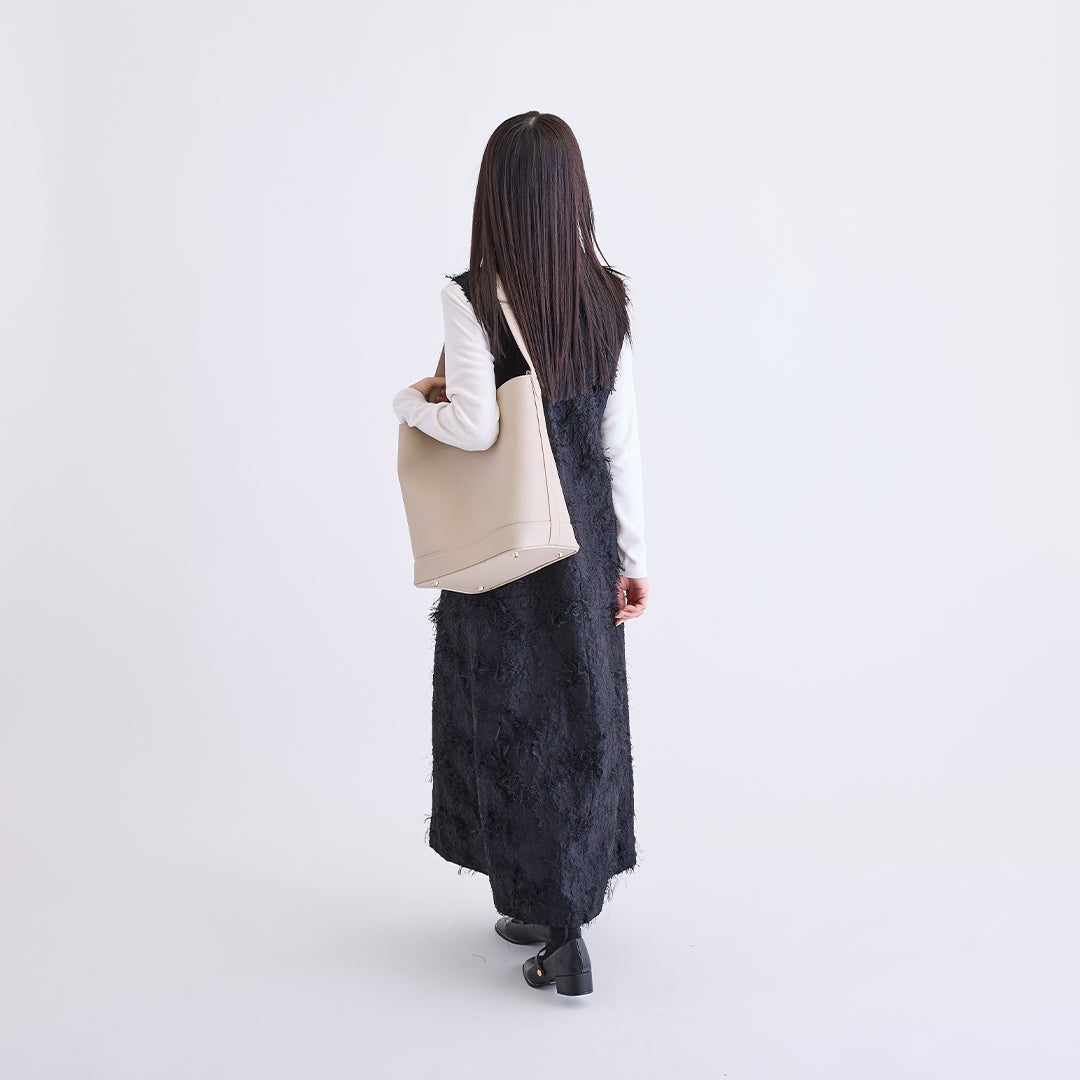 アイボリーのLサイズ巾着ボストンバッグを肩に掛けた女性