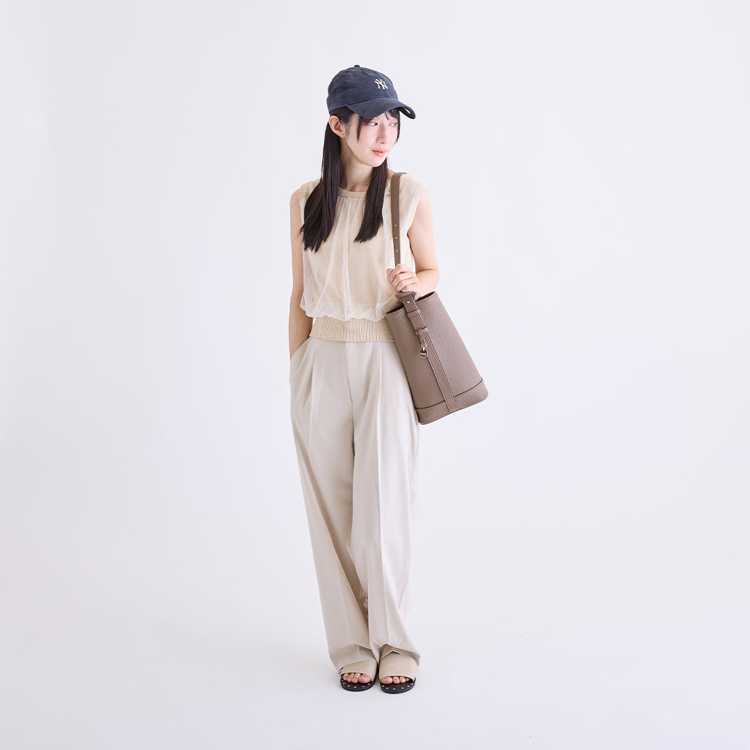 トープのLサイズ巾着ボストンバッグを肩に掛けた女性