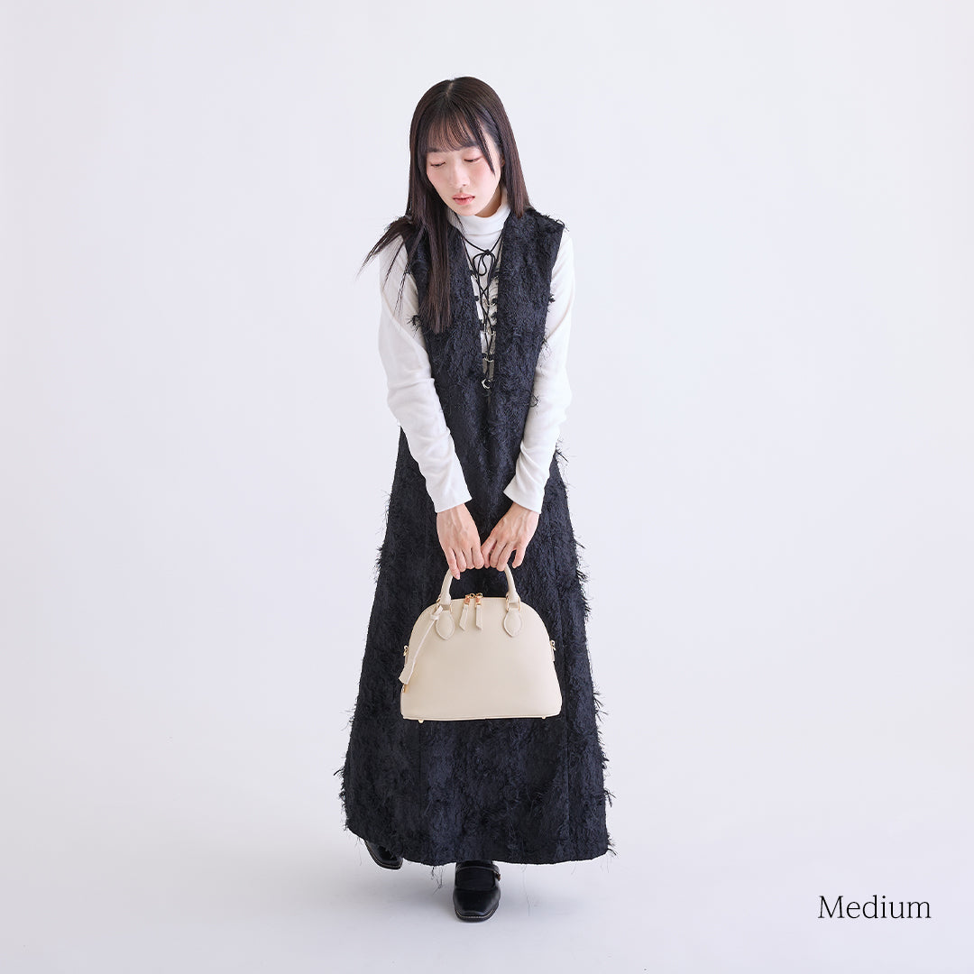 アイボリーのミディアムボストンバッグを手に持つ女性