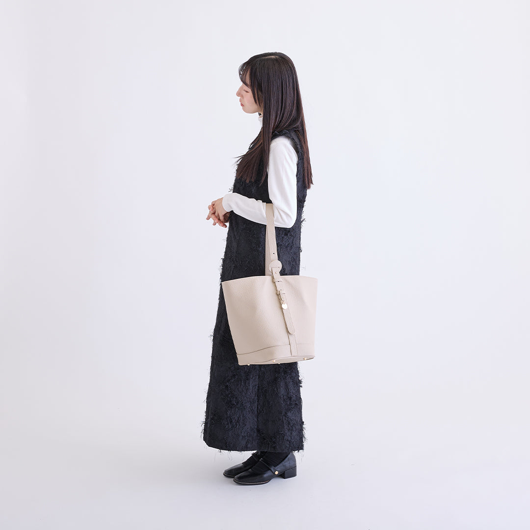 アイボリーのLサイズ巾着ボストンバッグを腕に掛けた女性