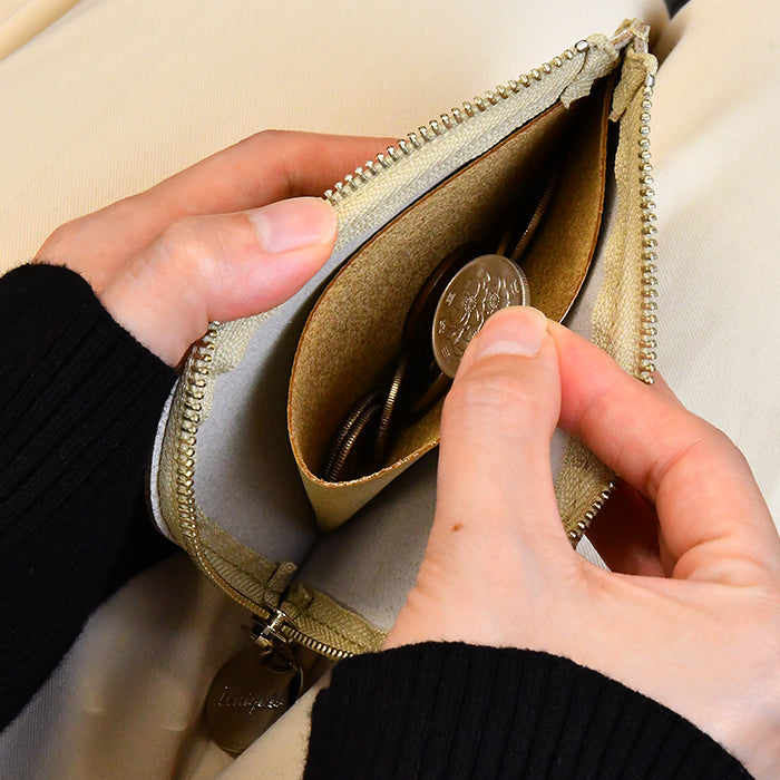ベージュのミニウォレットに硬貨を入れる手元
